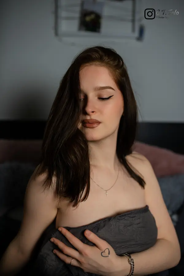Junge Frau in Dessous auf Bett mit Kopfkissen – warmes Boudoirfoto